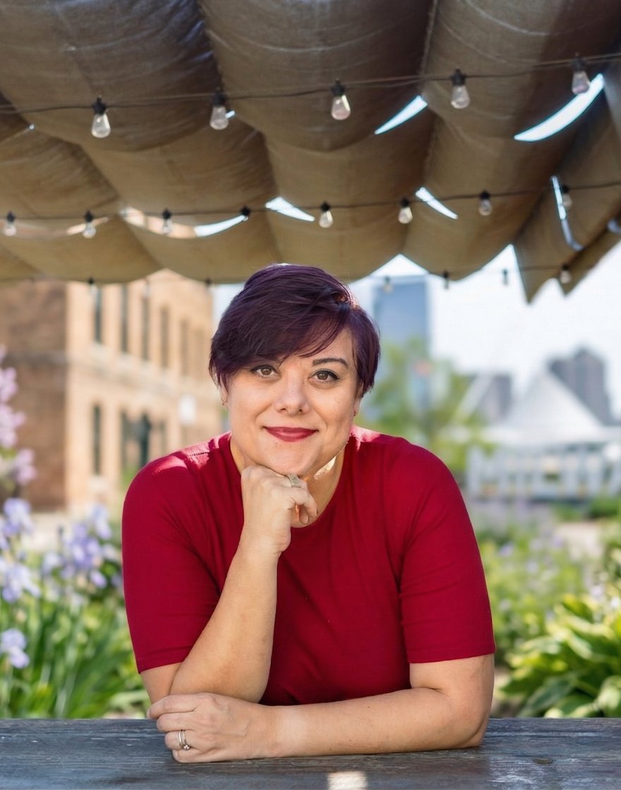Hazel Quimpo, founder of Practice Presence, in a relaxed warm portrait on a rooftop patio with greenery and city backdrop