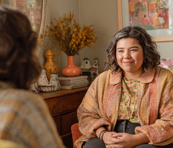 Client in a warm therapy office with colorful art, dried flowers, and cozy furniture