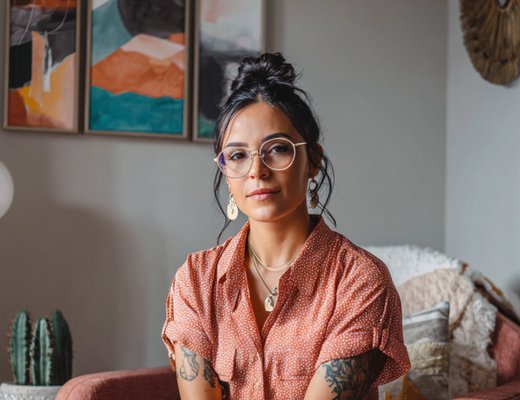 Latina therapist sitting in a beautifully styled office with abstract art, plants, and warm textiles